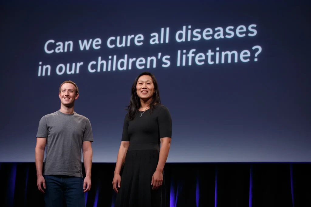 This image is the cover image of the story. The image shows Priscilla Chan and Mark Zuckerberg on stage, possibly at an event related to the Chan-Zuckerberg Initiative. Priscilla Chan is in a black dress, and Mark Zuckerberg is in a grey t-shirt.